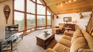 A spacious living room with large windows, a wooden ceiling, and a mounted deer head. - Stunning A-frame Home w/ Views, 10 Mi to Okanogan! (Brewster)