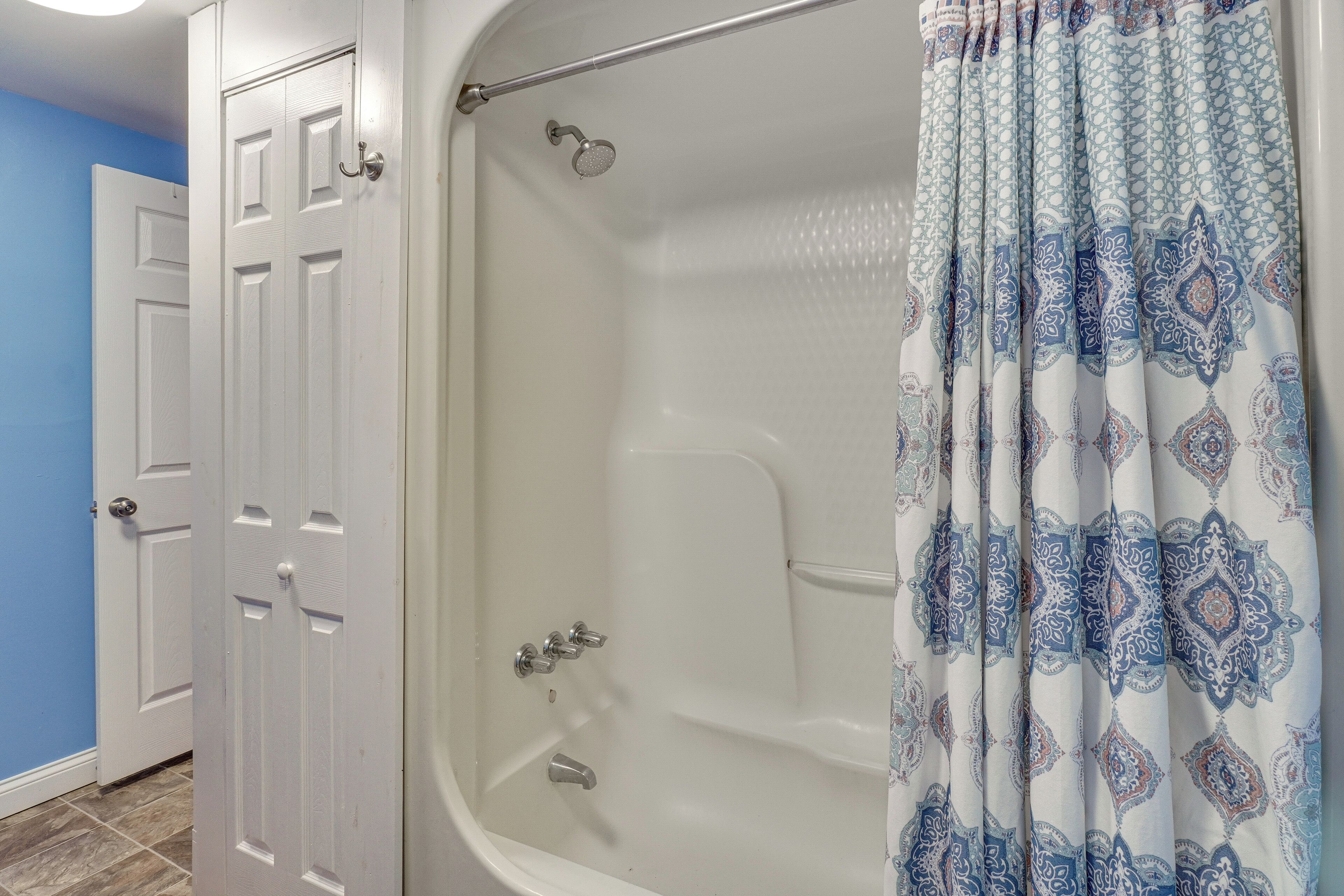 Une salle de bain avec une baignoire, une douche et deux portes blanches.