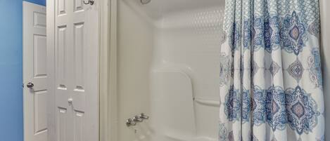Une salle de bain avec une baignoire, une douche et deux portes blanches.