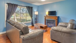 A living room with two leather sofas, a wooden coffee table, a fireplace, and a TV on a stand.