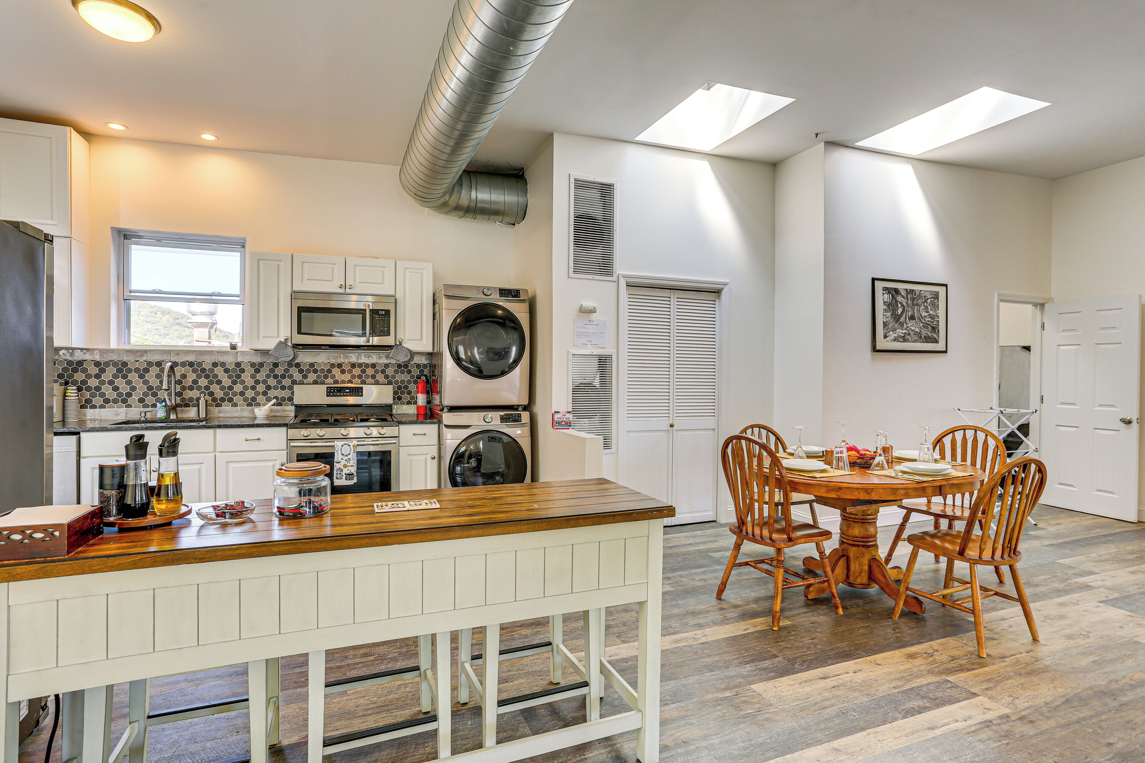 A modern kitchen with a central island, built-in appliances, and a dining area with wooden chairs.