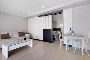A modern living room with a sofa, coffee table, and dining area with chairs.