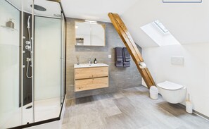 A modern bathroom with a glass shower enclosure, a wooden vanity, a mirror, and a toilet.