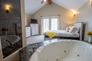 A modern bedroom with a large bed, a bathroom with a bathtub, and a walk-in closet. - Cheery 2-story Coach House - Beachwalk Resort (Michigan City)