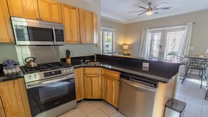 A modern kitchen with wooden cabinets, stainless steel appliances, and a black countertop.