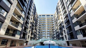 Un hotel de varios pisos con un atrio central, zona de piscina y un letrero que dice "BUILDING 1".