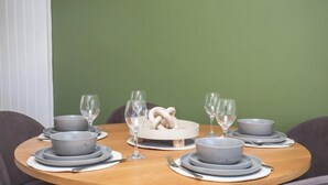 Mesa de comedor dispuesta con cuencos grises, platos y copas de vino, centrada en un adorno blanco.