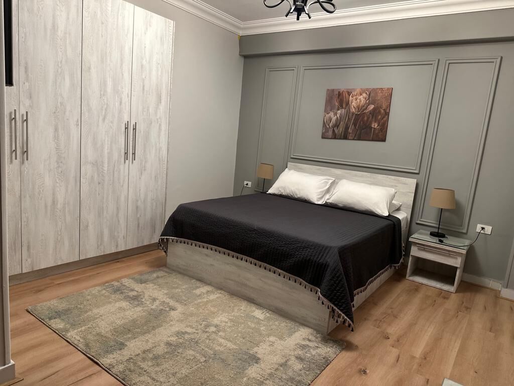 A bedroom with a bed, nightstands, a wardrobe, and a painting on the wall.