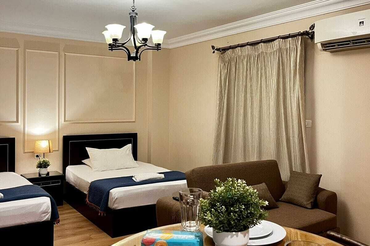 Ein Hotelzimmer mit zwei Betten, einem Esstisch mit Tellern und Gläsern, einer Kristallleuchtre und einer Klimaanlage.