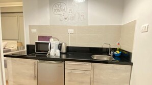 A compact kitchen with a dishwasher, a coffee maker, and a sink. - Chelay studios  (New Cairo)