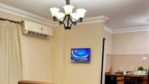 A hotel room with a sofa, two beds, a desk, and a television. - Chelay studios  (New Cairo)