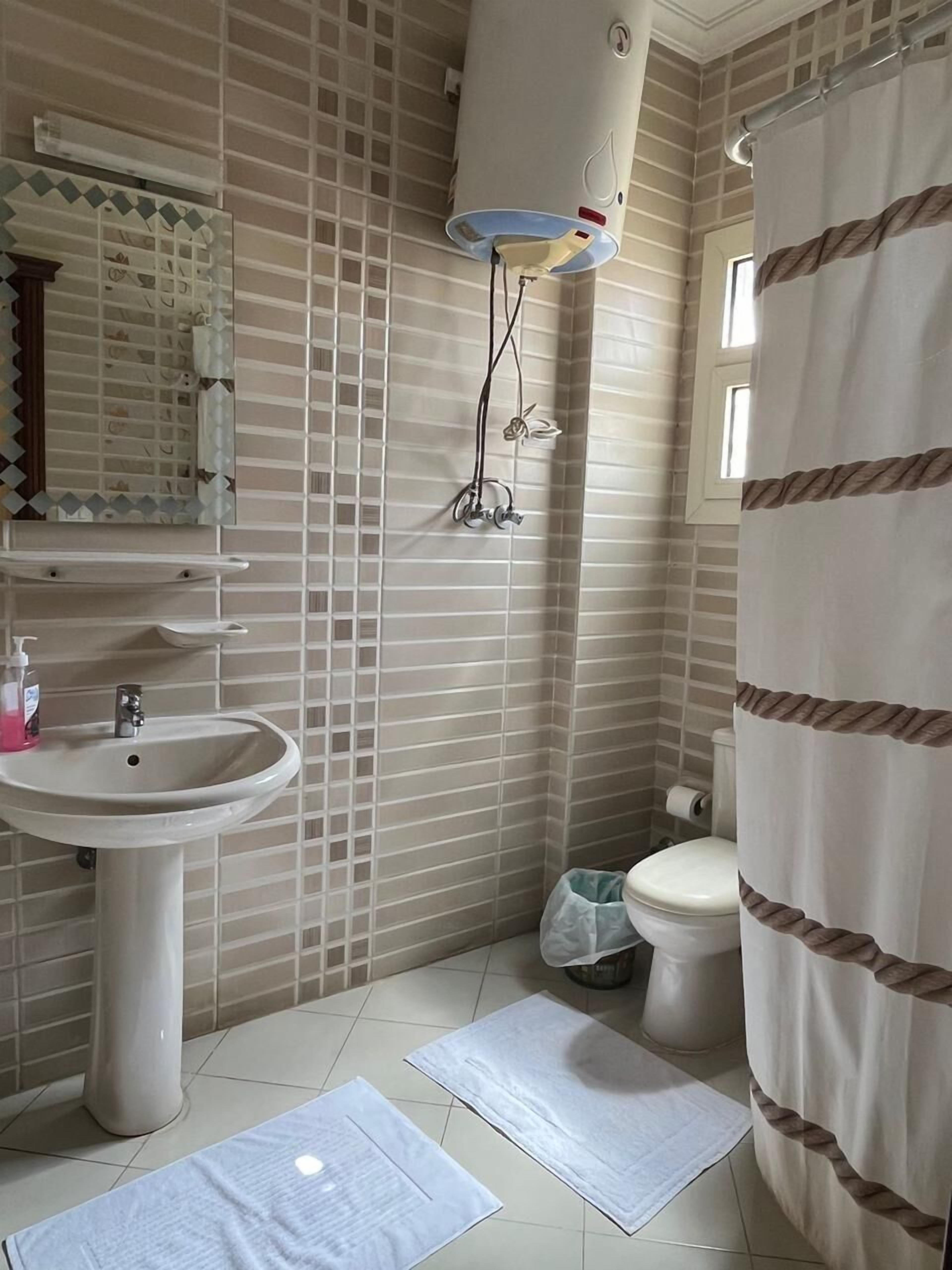 Un baño con lavamanos, espejo, cortina de ducha y un inodoro.