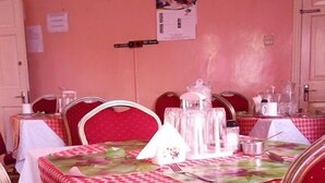 A dining area with red chairs and tables covered in checkered tablecloths. - White highlands Inn Eldoret (Eldoret)