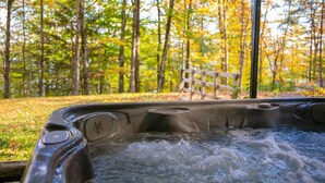 Ein Whirlpool mit Holzterrasse in einer bewaldeten Gegend.