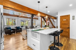 A spacious kitchen with a central island, wooden beams, and pendant lighting. - Mont Owl's Head - Carlton (Potton)