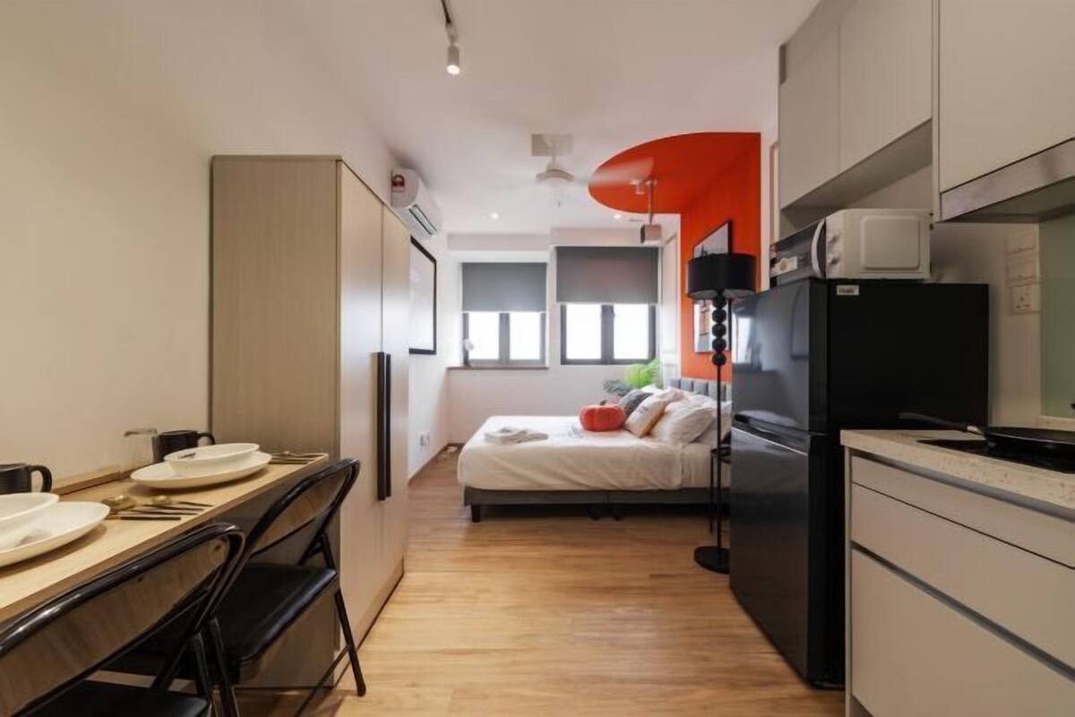 A compact hotel room with a kitchenette, a bed, and a dining area.