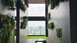 A corridor with vertical gardens, a green carpet, and two green bean bag chairs. - The Riv - Riveria City KL Sentral by Sleepy Bear (Kuala Lumpur)