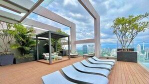 A rooftop lounge area with modern seating and a glass enclosure with plants. - The Riv - Riveria City KL Sentral by Sleepy Bear (Kuala Lumpur)