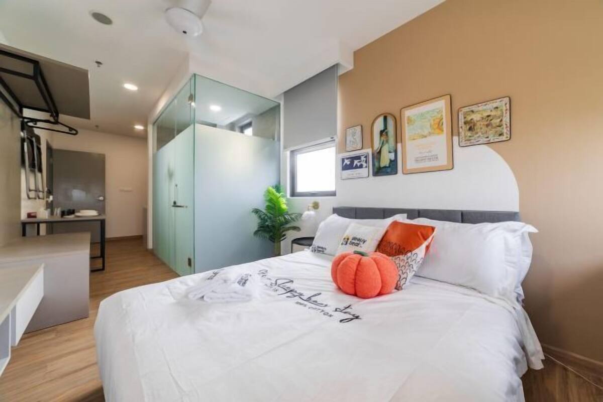 A modern bedroom with a bed, a desk, and a glass partition.