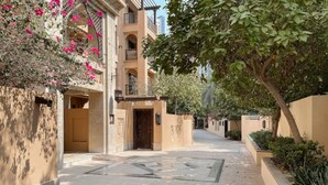 Une cour intérieure avec une entrée centrale, entourée d’immeubles de couleur beige dotés de balcons et d’éléments décoratifs.