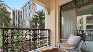 Un balcon donnant sur des immeubles imposants, avec une chaise et une table.