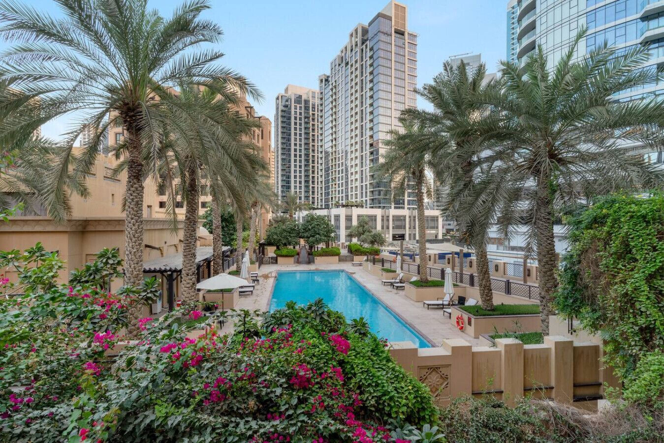 A pool area with palm trees and a view of high-rise buildings.