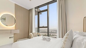 Una moderna camera d'albergo con un letto grande, vista sulla città e uno specchio rotondo.