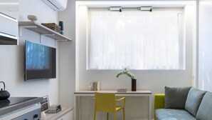 Et moderne køkken med et indbygget komfur, et spiseområde med en gul stol og en grå sofa.