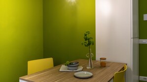 Et spiseområde med et træbord, en skål, en tallerken, en vase med en plante og et glas.