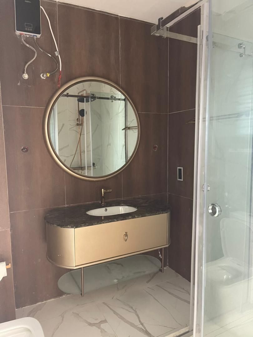 Un baño con un espejo redondo, un lavamanos y una zona de ducha.