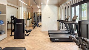 A modern gym with treadmills, weight machines, and a rowing machine.