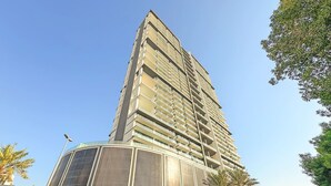 Ein hohes, modernes Gebäude mit mehreren Balkonen und einer gewölbten Glasfassade.
