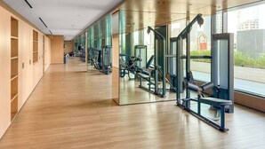 Ein modernes Fitnessstudio mit Holzböden, Spiegelwänden und verschiedenen Trainingsgeräten.