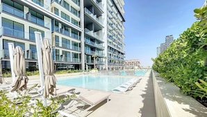 Ein modernes Hotel mit Schwimmbad, Liegestühlen und einem gepflegten Garten.