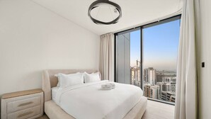 Een moderne hotelkamer met een groot bed, een nachtkastje en uitzicht op de stadslijn door middel van ramen van de vloer tot aan het plafond.