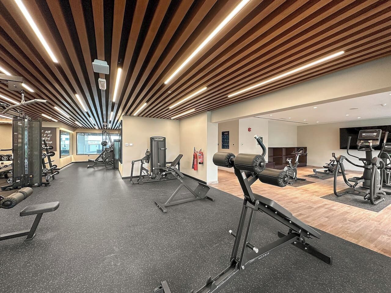 A gym with exercise equipment, a wooden ceiling, and a fire extinguisher.