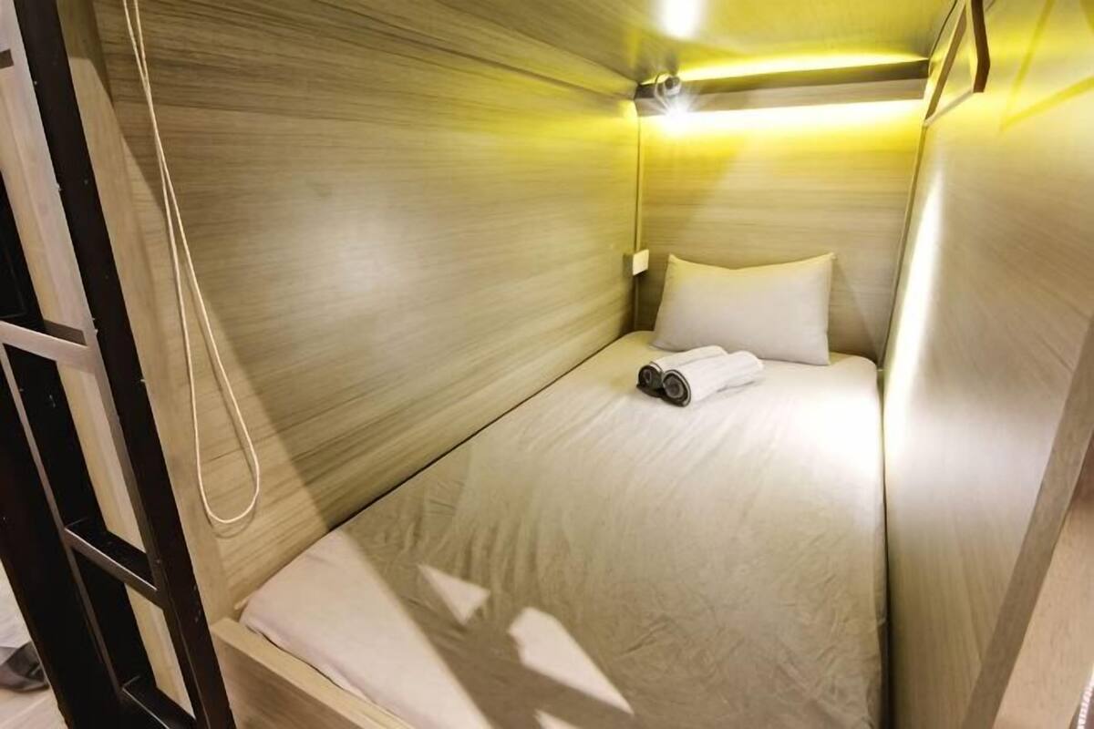 A single bed with a headboard, a bedside table, and a lamp.