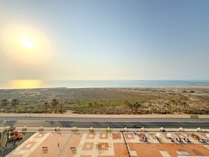 A coastal road with a paved area in the foreground, a clear sky, and a distant view of the sea. - FIRST CLASS | Studio | Panoramic Sea Views (Al Jazeera Al Hamra)