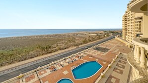 Un hôtel avec une piscine, situé près d’une route et offrant une vue sur la plage.