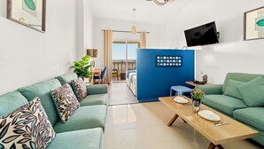 Un salon moderne avec un canapé, une table à manger, un téléviseur et une vue sur le balcon.