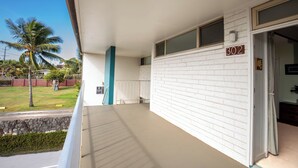 Een hotelkamer met een gevel van witte bakstenen, een balkon met uitzicht op palmbomen, en een deur met het nummer 302.