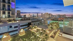 Un hôtel moderne avec une terrasse sur le toit offrant une vue sur la ville au crépuscule.