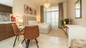 A modern hotel room with a bed, a desk, a chair, a television, and a large window. - FIRST CLASS | Studio | Chic & Comfy in Jewelz (Arjan)