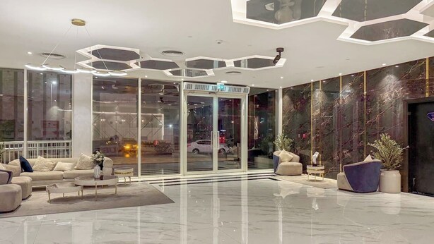 A modern lobby with a glass entrance, a seating area with sofas and a coffee table, and a decorative ceiling. - FIRST CLASS | Studio | Chic & Comfy in Jewelz (Arjan)