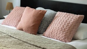 A bed with a textured green bedspread and four pillows in shades of pink and gray. - Spacious Apartment | Air Conditioning, Balcony, close to the Stadium (Warszawa)