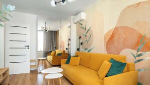 Ein modernes Wohnzimmer mit einem gelben Sofa, einem weißen Couchtisch und einem großen, abstrakten Wandbild.