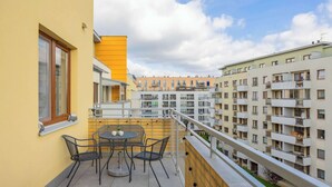 Un balcón con mesa y sillas, con vistas a una zona residencial con varios edificios de apartamentos.