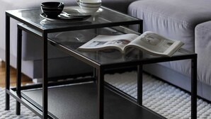 Una sala de estar moderna con una mesa de centro de vidrio, un sofá con cojines estampados y un jarrón decorativo.