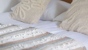 Una cama bien hecha con un edredón a rayas, un cabecero de madera y dos almohadas color crema.