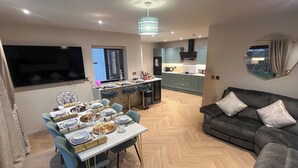A modern living room with a dining area, a sofa, and a kitchen in the background.
